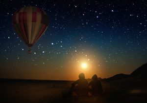 Paar vor nächtlichem Sternenhimmel mit Freiluftballon, Romantik pur